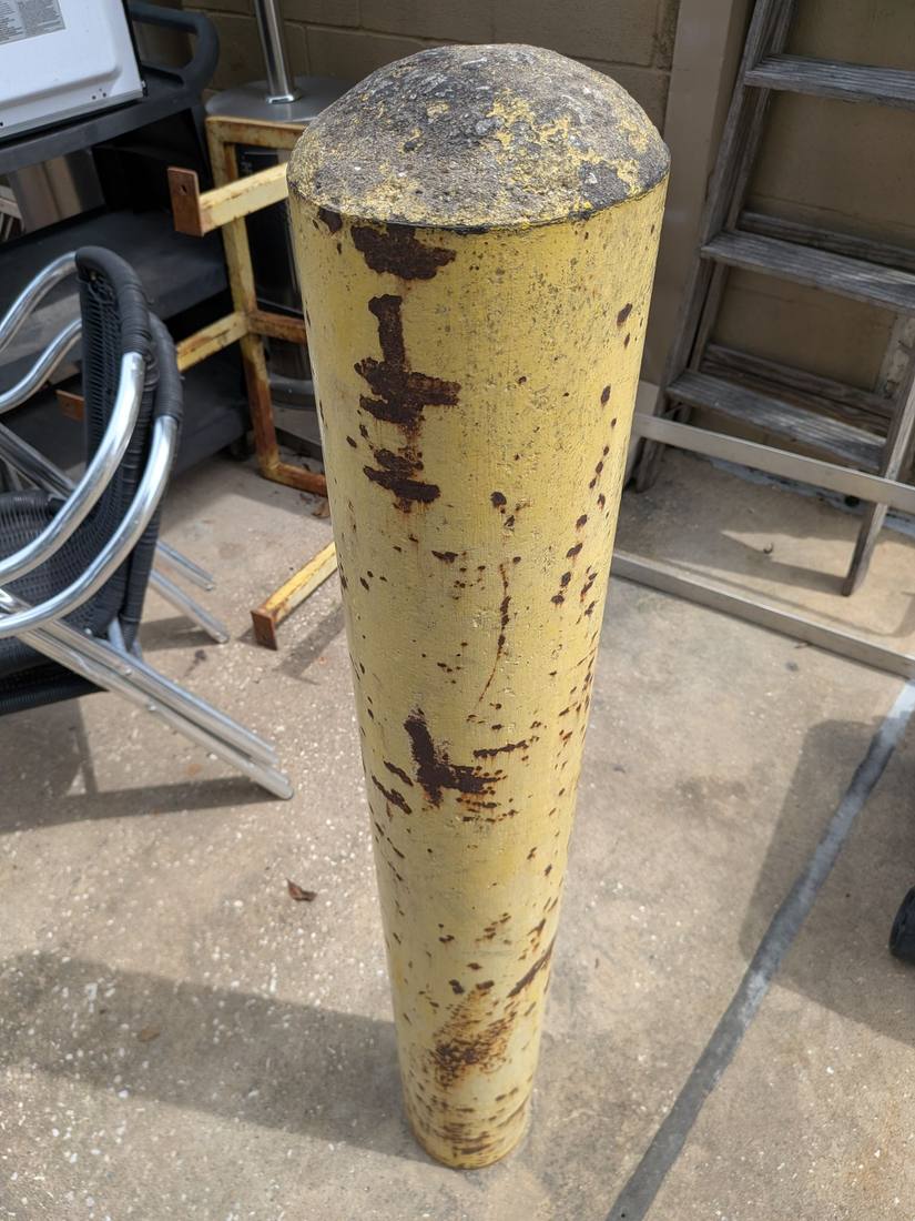 Original bollard sleeve with chalked yellow paint and rust bleeding through