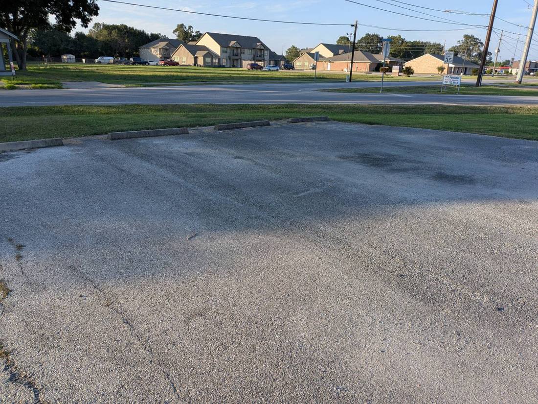 Faded asphalt parking lot with worn-out stall lines before restriping