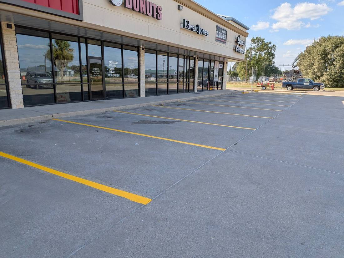 Repainted yellow parking stalls on concrete at a Fort Bend County retail center